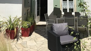 A patio area with outdoor furniture, a table, and potted plants. - 3-star listed house with south-facing courtyard in La noue (Sainte-Marie-de-Ré)
