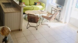 A modern kitchen with a built-in sink and a dining area with wicker chairs and a round table. - 3-star listed house with south-facing courtyard in La noue (Sainte-Marie-de-Ré)