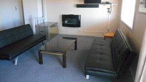 Ein kompakter Wohnraum mit Sofa, Couchtisch, Fernseher und Heizkörper.