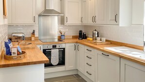 A kitchen with white cabinets, a stainless steel range hood, a toaster, and a coffee maker. - 3 bedroom accommodation in St Mawgan (St Mawgan)