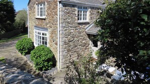 A stone house with a sloped roof, a chimney, and a paved driveway. - 3 bedroom accommodation in St Mawgan (St Mawgan)