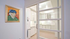 Une cuisine moderne avec des meubles blancs et une porte vitrée donnant sur un balcon.