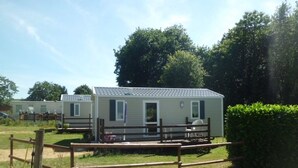 A row of mobile homes with a wooden fence and a hedge in the foreground.