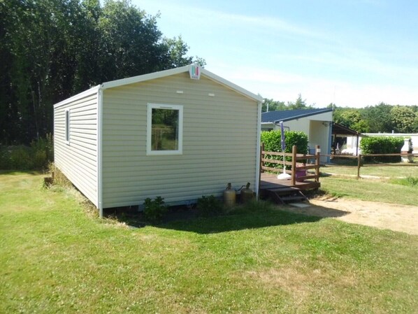 A small, single-story mobile home with a front porch and a small window.