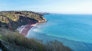 Eine Küstenlandschaft mit Strand, felsigen Klippen und blauem Himmel.