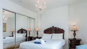Ein Schlafzimmer mit einem großen Bett, einem Spiegel, einer Chandelüster und zwei Nachttischen mit Lampen.