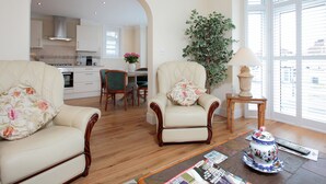 Een woonkamer met twee fauteuils, een salontafel en een eethoek met een tafel en stoelen.