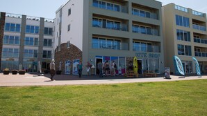 Un edificio de varios pisos con un letrero que dice 'Kite Shop' y una exhibición de tablas de surf en el exterior.