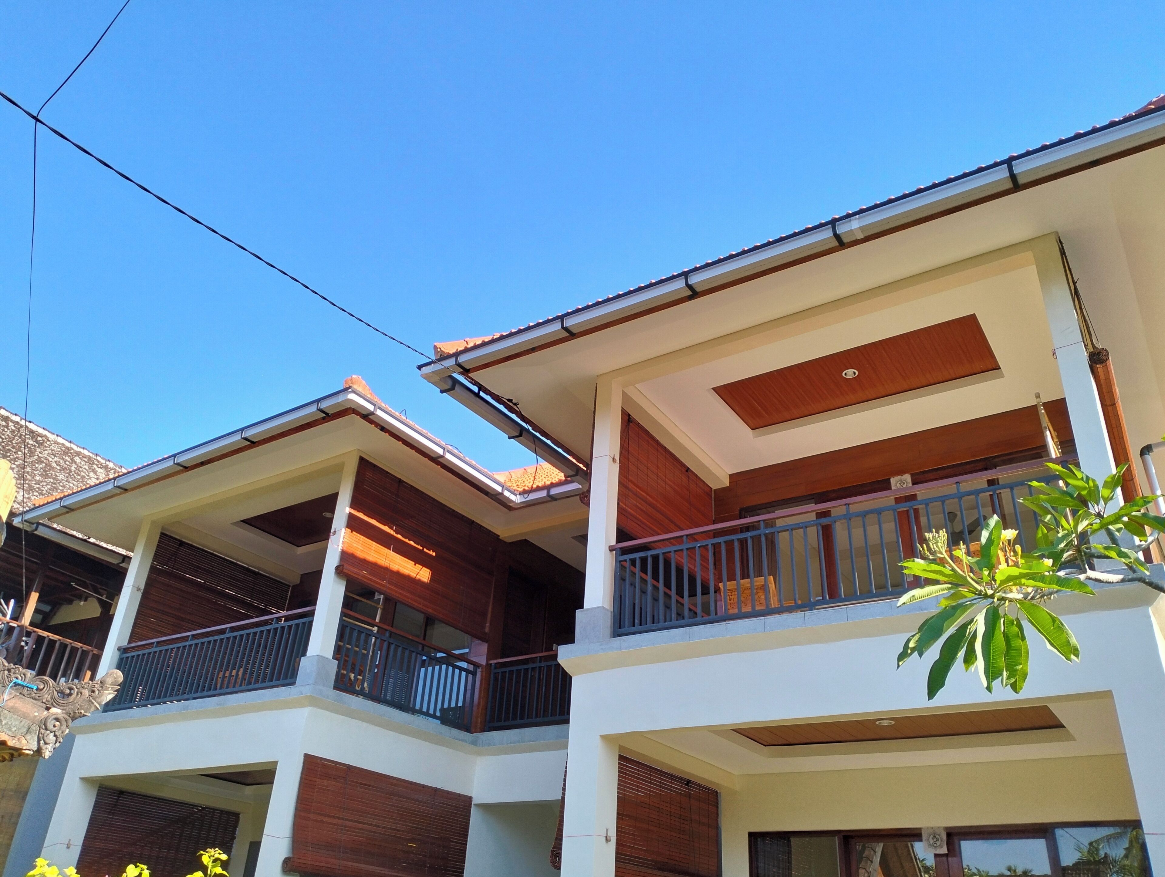 Un edificio residencial de varios pisos con balcones, fachada de madera y un cielo azul despejado.