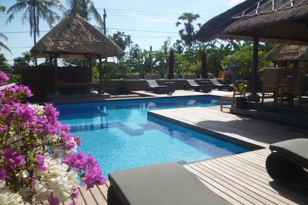 Una piscina al aire libre, sombrillas, sillones reclinables de piscina
