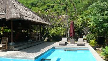 Una piscina al aire libre, sombrillas, sillones reclinables de piscina
