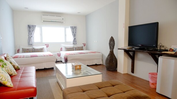 A hotel room with two beds, a TV, a coffee table, and a sofa. - Rusty inn (Hengchun)