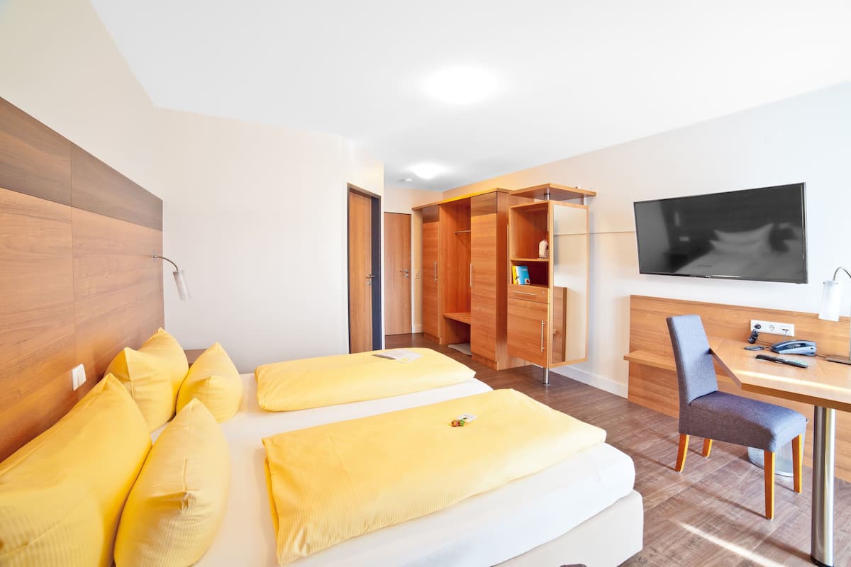 Ein modernes Hotelzimmer mit einem Bett, einem Schreibtisch, einem Stuhl und einem Fernseher.