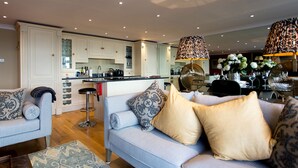 A modern kitchen with white cabinets, a central island, and a dining area with a patterned tablecloth.