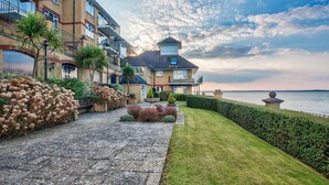 A residential building with a paved driveway, a well-maintained lawn, and a view of the sea.