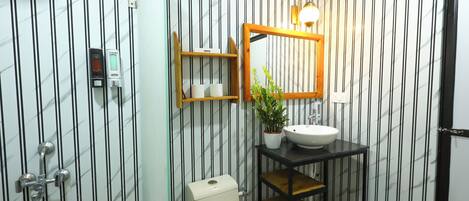 A bathroom with a striped wall, a toilet, a sink, a mirror, and a shelf with toiletries.
