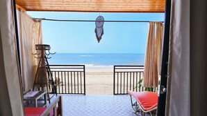 A room with a view of the beach, a dreamcatcher hanging, and a table with chairs. - Simrose Resort South End of Agonda Beach (Canacona)