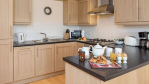 Una cucina moderna con mobili in legno, un lavello, un fornello, un forno a microonde e un bollitore.