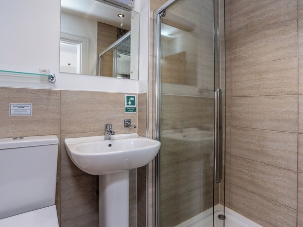 A bathroom with a glass-enclosed shower, a sink, and a mirror.