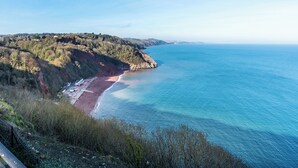 Un paysage côtier avec une plage, des falaises rocheuses et un ciel dégagé.