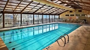 An indoor swimming pool with clear glass walls, a metal roof, and a lifeguard chair. - 3 bedroom, 3 bath, indoor and outdoor pools, 2nd floor in gated Pointe Royale (Branson)