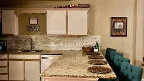 A kitchen with white cabinets, a granite countertop, a sink, and a bar sign. - 3 bedroom, 3 bath, indoor and outdoor pools, 2nd floor in gated Pointe Royale (Branson)