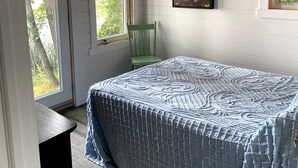 Un dormitorio con cama, ventilador de techo y ventanas amplias.