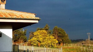 Een gebouw met een pannendak en een omheind gebied met bomen op de achtergrond.