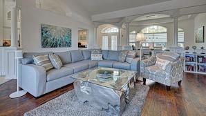 A spacious living room with a large sectional sofa, a glass coffee table, and a patterned armchair. - Bella Vista | Pool | Spa | Lake front | Lounge (Rotonda West)