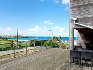 Une terrasse en bois, agréée de mobilier d’extérieur, offrant une vue sur la côte.