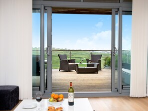 Un balcon avec une table dressée pour deux personnes, une bouteille de vin et un panier de fruits.
