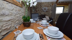 A dining table set with white plates, bowls, cutlery, and a potted plant.