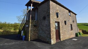 A stone building with a wooden balcony, a door, and a window.