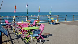 Een terras aan zee met kleurrijke stoelen en tafels, met uitzicht op de oceaan.