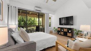 Ein modernes Schlafzimmer mit einem großen Bett, einem Fernseher und einer Schiebetür zum Balkon.