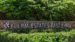 Eine Steinmauer mit dem Schriftzug 'KUILIMA ESTATES EAST' und einem Logo.