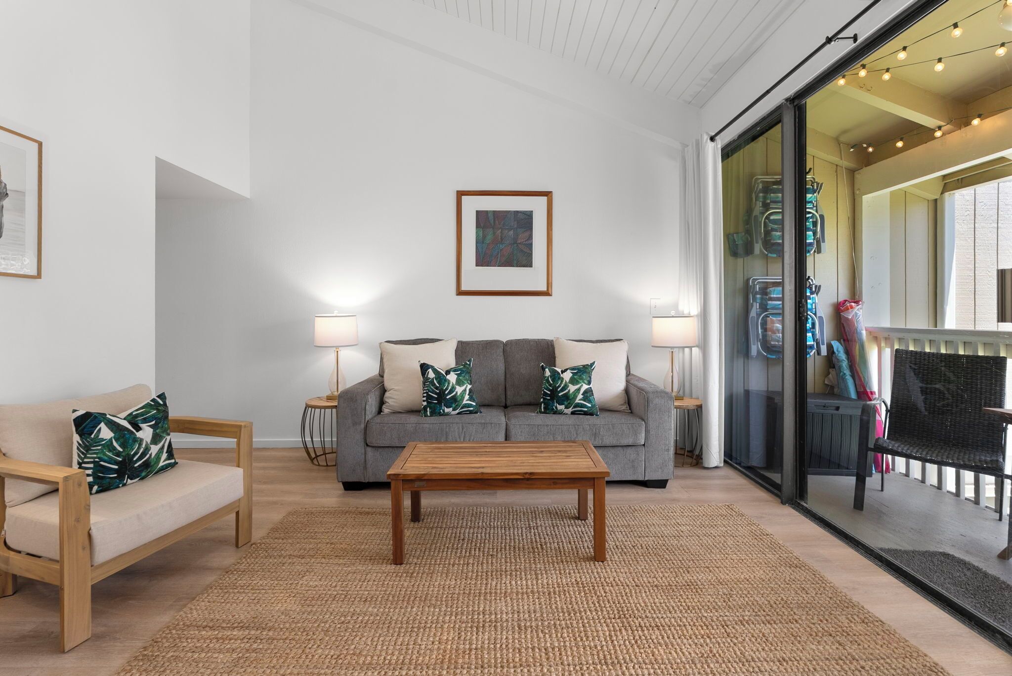 A living room with a sofa, a coffee table, and a glass door leading to a balcony.