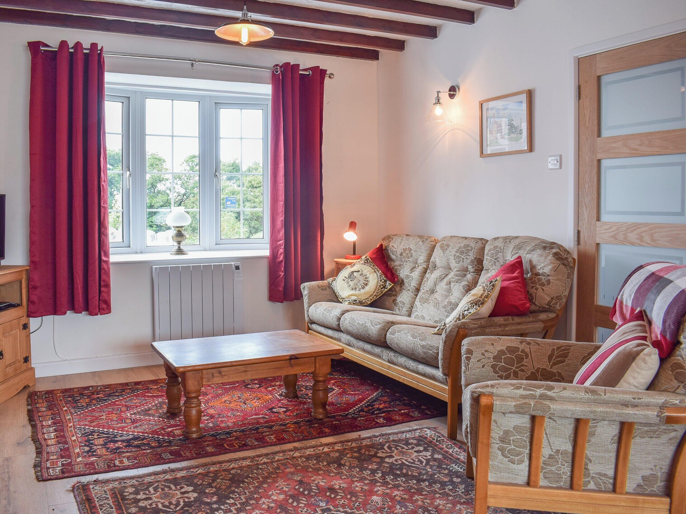 Tunnelmallinen olohuone, jossa on sohva, puinen sohvapöytä ja kuviollinen matto.