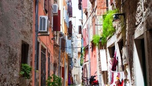 A narrow cobblestone street flanked by multi-story buildings with balconies, air conditioning units, and potted plants. - Apartment in Rovinj with Terrace, Air condition, WIFI (3483-4) (Rovinj)