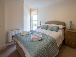 A bedroom with a bed, a radiator, a nightstand, and a window. - 2 bedroom accommodation in Shanklin (Shanklin)