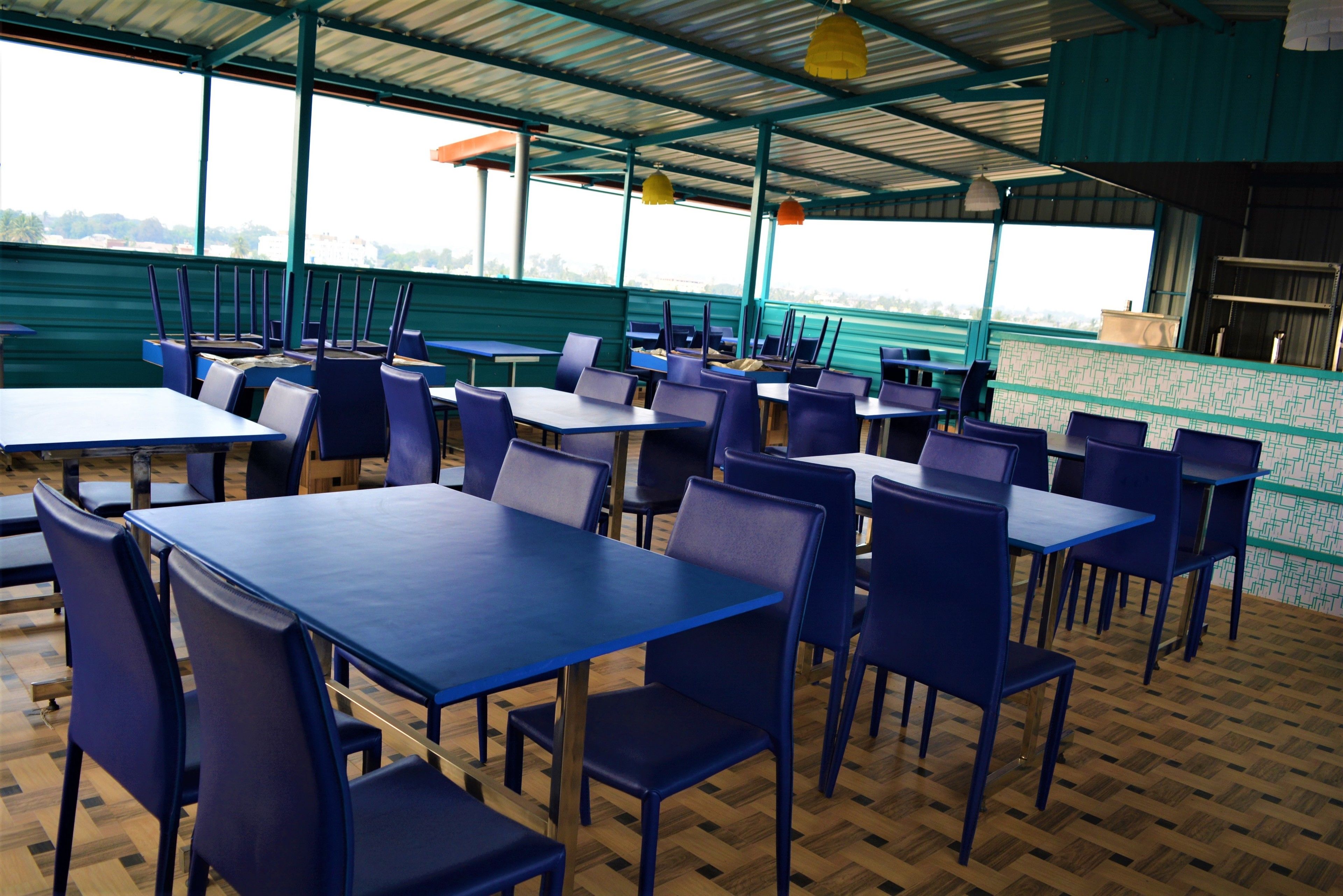 A restaurant with tables and chairs arranged in rows, large windows, and a view of the outside.