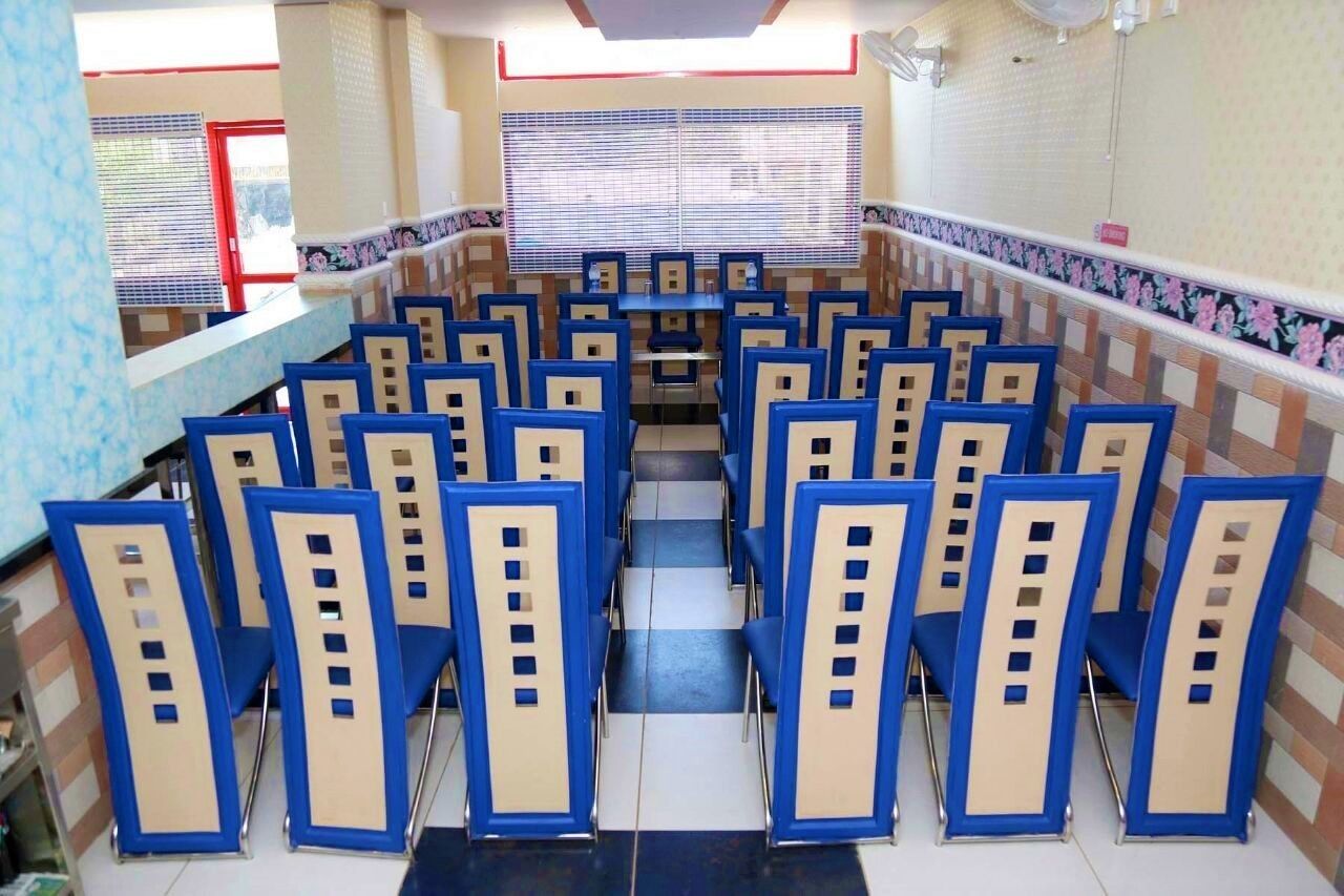 A conference room with rows of blue and beige chairs, a central table, and patterned walls.