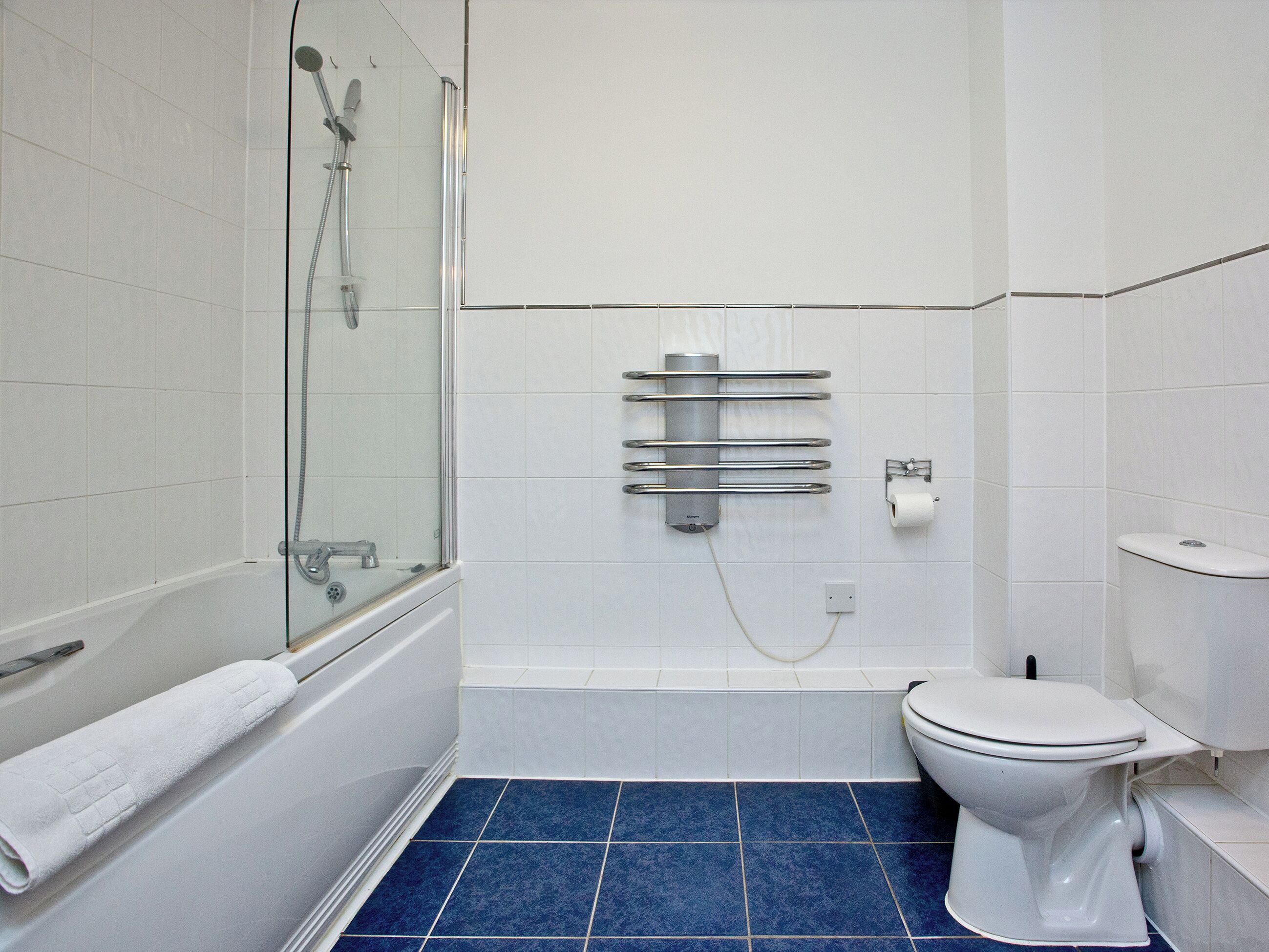 A bathroom with a glass-enclosed shower, a toilet, and a towel rack.