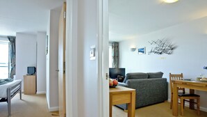 Et værelse med seng, skrivebord, fjernsyn, sofa og spisebord.