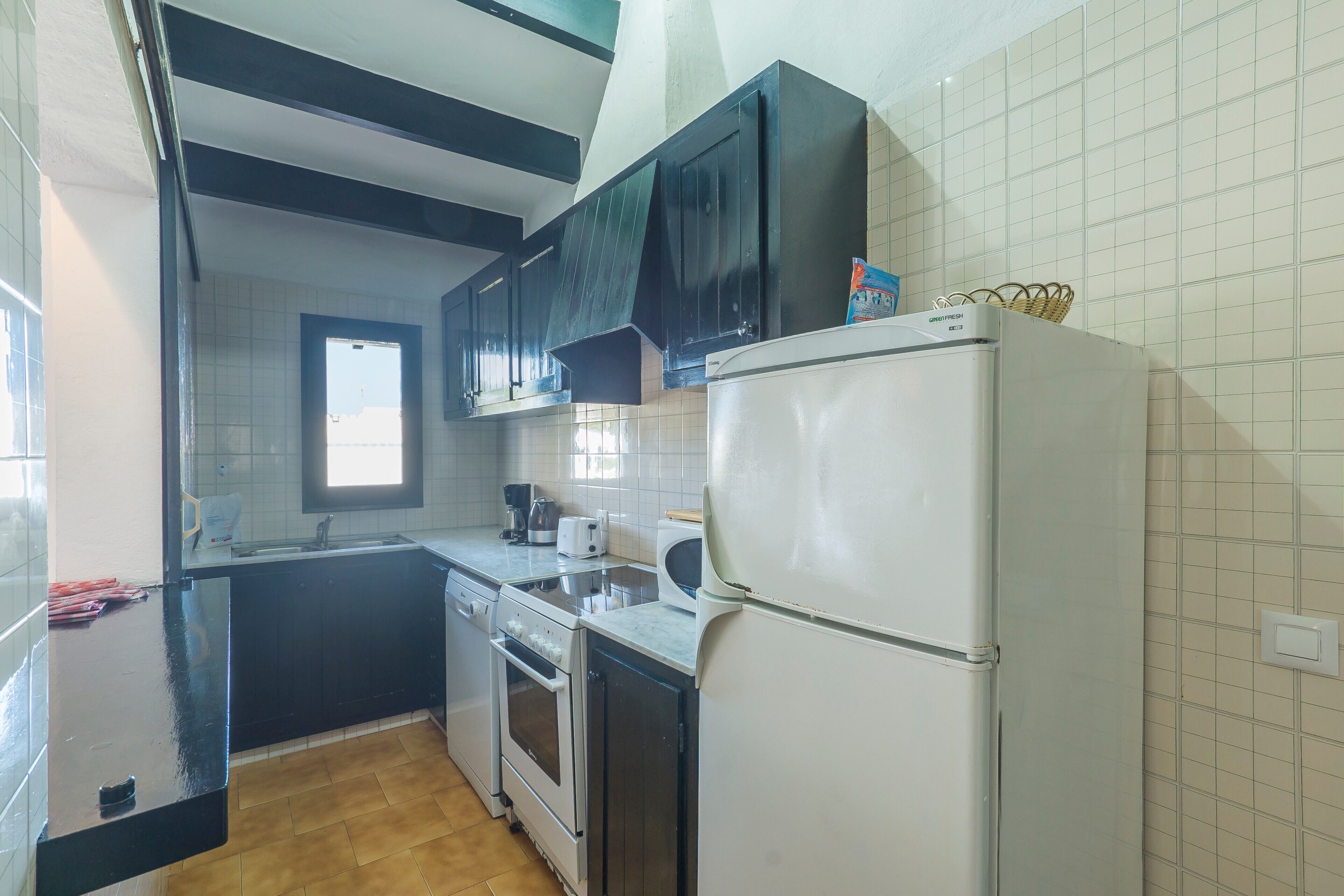 Una cocina con refrigerador, horno y lavamanos.