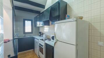 Una cocina con refrigerador, horno y lavamanos.