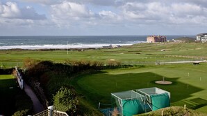 A coastal golf course with a view of the ocean and a large building in the distance. - Bredon Court, Poseidon Penthouse (Newquay)
