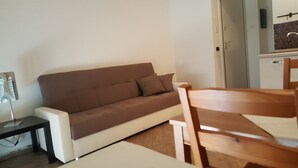 Ein modernes Wohnzimmer mit einem braunen Sofa, einem Holzesstisch und einem kleinen Beistelltisch.