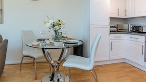 A dining table with chairs, a vase with flowers, and a bottle of wine. - Comfort and luxury in a sea front location with panoramic sea views. (Paignton)