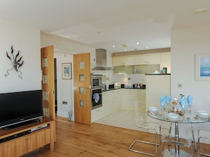A modern kitchen with a dining area, wooden flooring, and a flat-screen TV. - A breathtaking apartment in a unique position. (Westward Ho!)